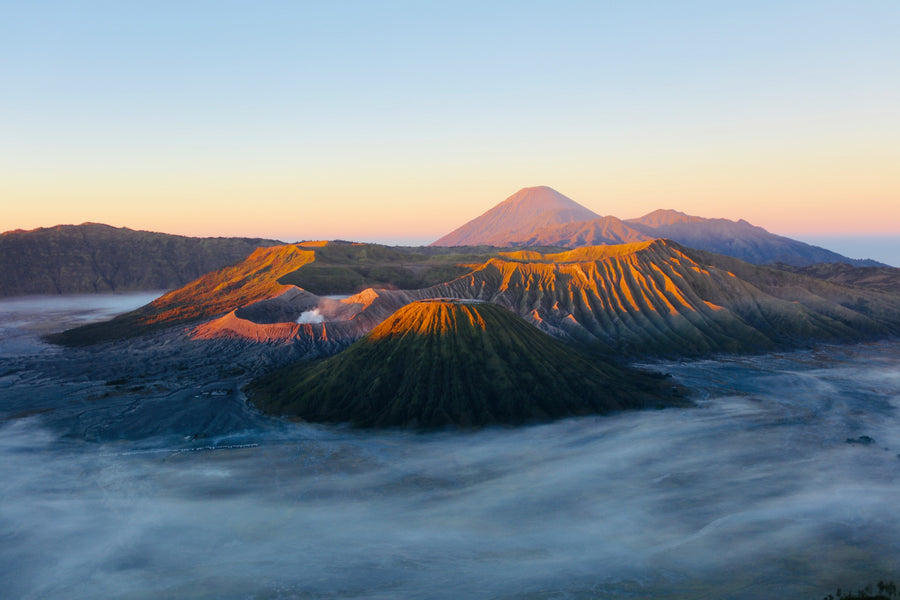 Mount Bromo and nearby volcanoes above a sea of clouds at sunrise
