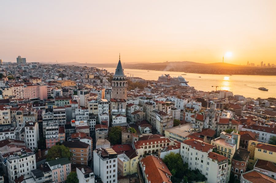 Galata Tower above the rooftops of Istanbul at sunset, with the Bosphorus behind