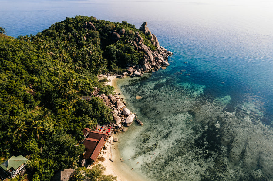 A sandy beach between granite boulders and jungle on Koh Tao, seen from above