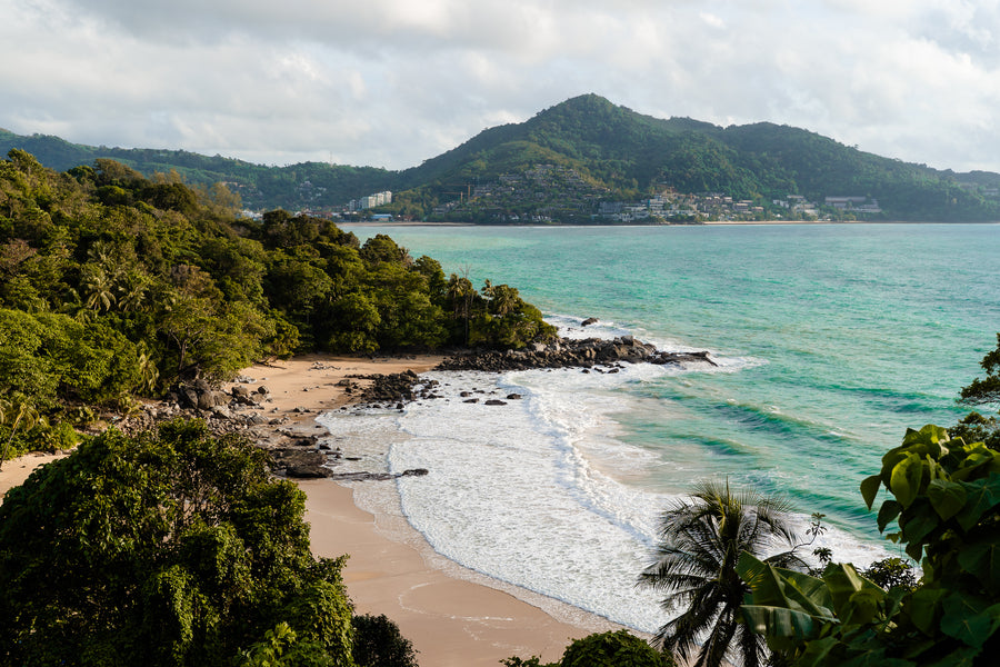 A sandy bay between green hills and jungle on the coast of Phuket
