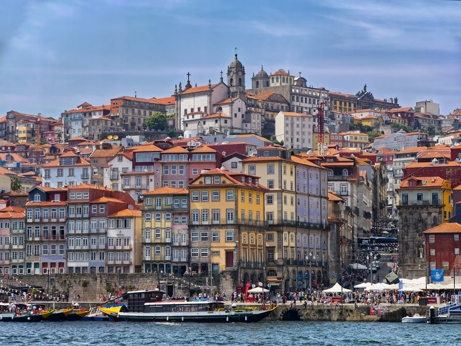 Colourful houses of Ribeira stacked above the Douro river in Porto, with boats along the quay