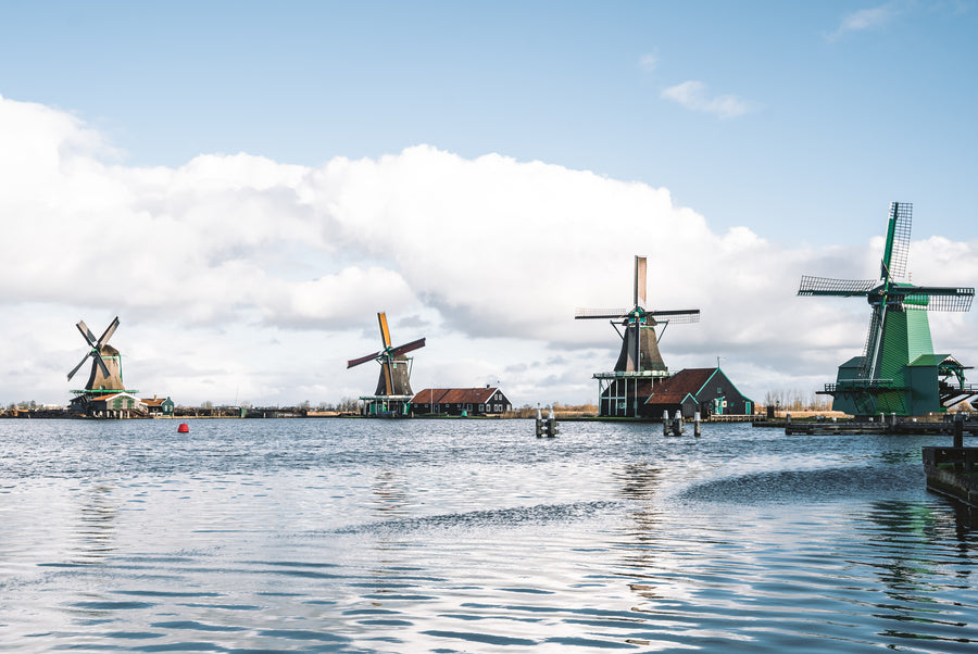 Vier molens langs de Zaan bij de Zaanse Schans onder een blauwe lucht