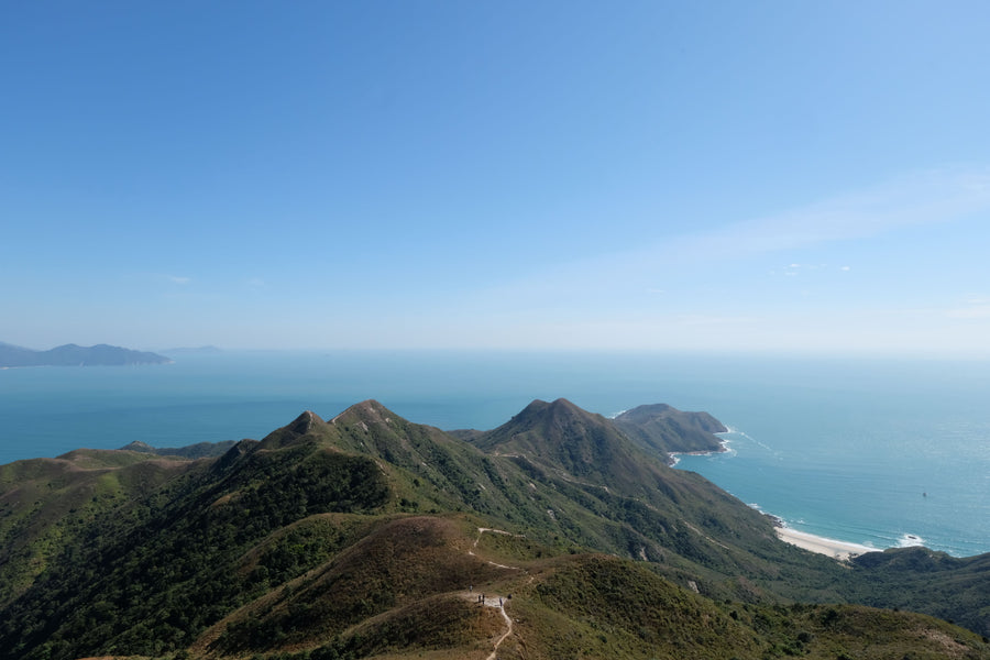 Een groene bergkam met wandelpad boven de kust van Hong Kong Island