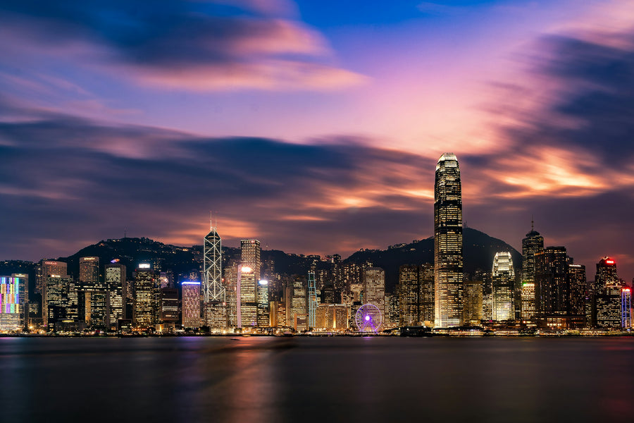 De skyline van Hong Kong Island aan de overkant van Victoria Harbour bij schemering