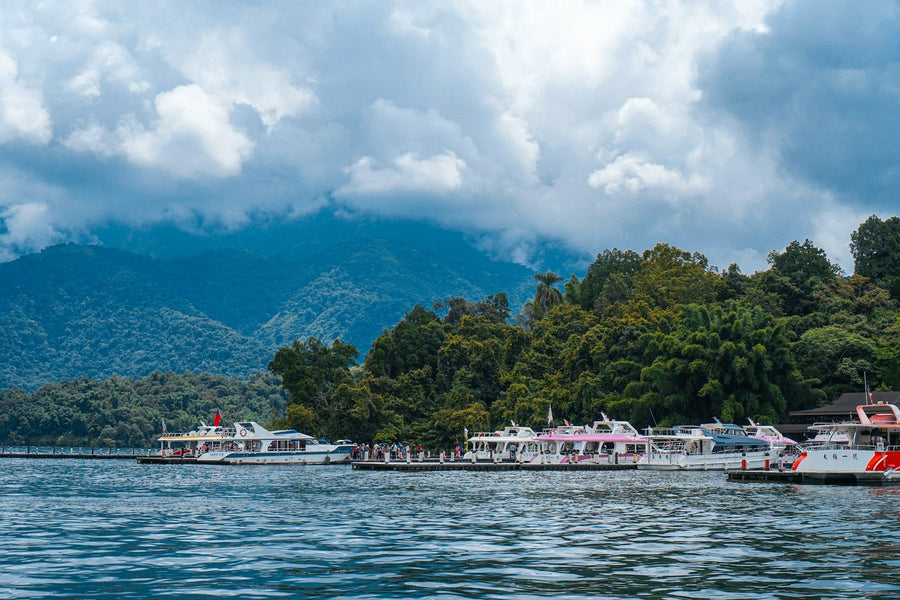 Boats at a pier on Sun Moon Lake with green mountains behind, Taiwan