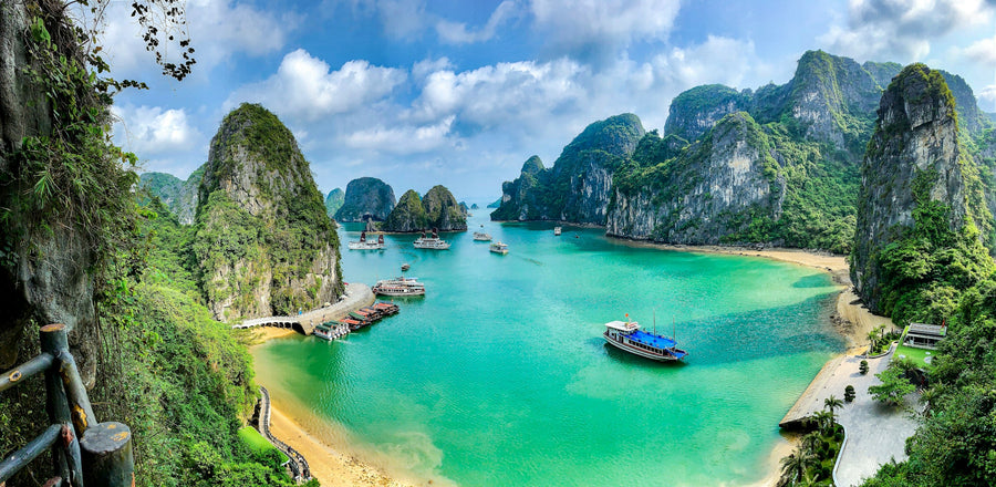 Limestone islands and a turquoise bay with boats in Ha Long Bay