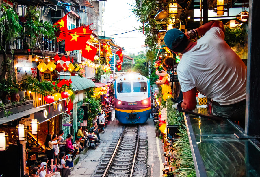 A train passing between cafés and lanterns on Train Street in Hanoi